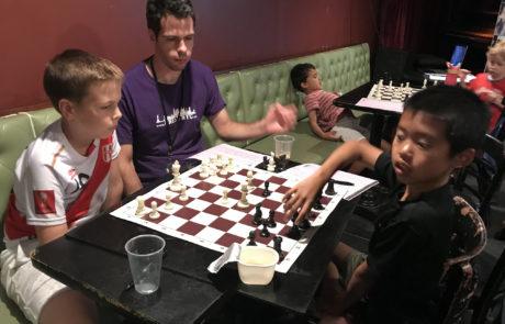 Coach and students playing chess at an in-club lesson