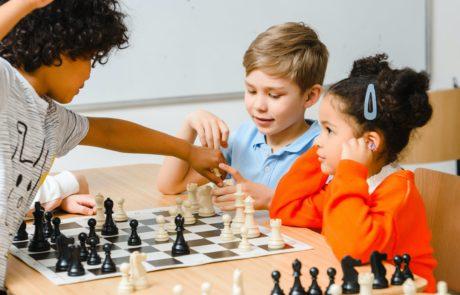Children playing chess together in a group lesson